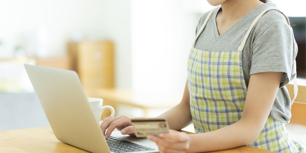 ノートPCを操作してクレカを見ている主婦