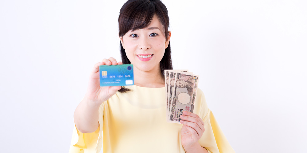 お金とクレジットカードを手にする女性