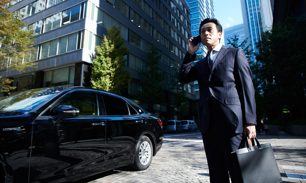 電話しているビジネスマンと社用車