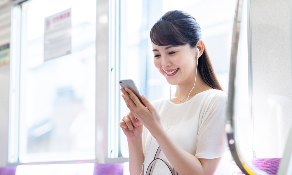 電車でスマホをいじる女性