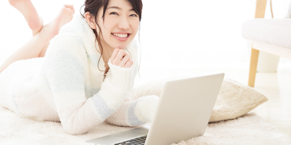 部屋着でノートPCを触る女性