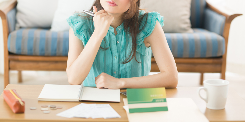 通帳と家計簿を見る女性