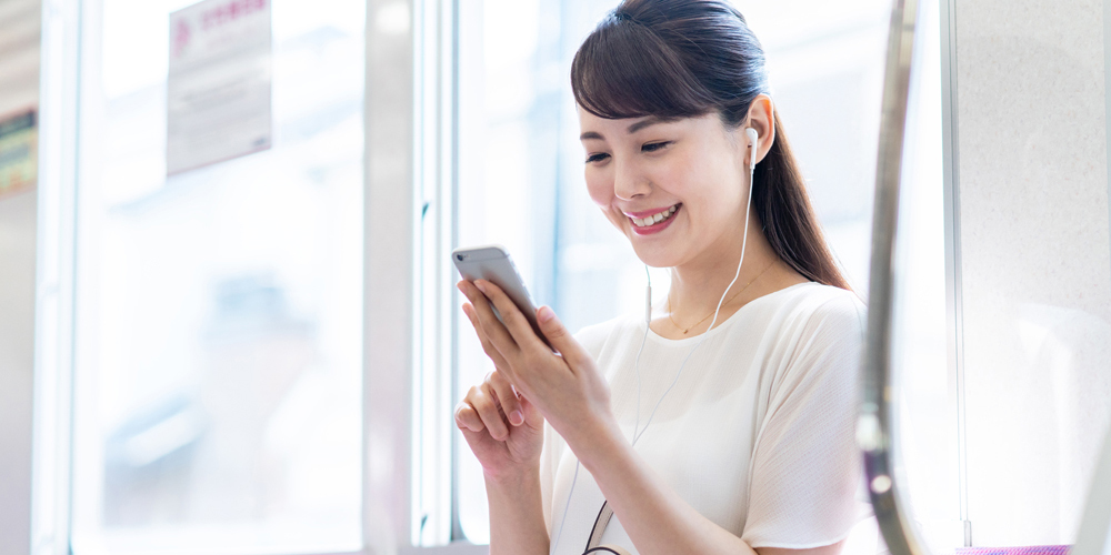 電車でスマホをいじる女性