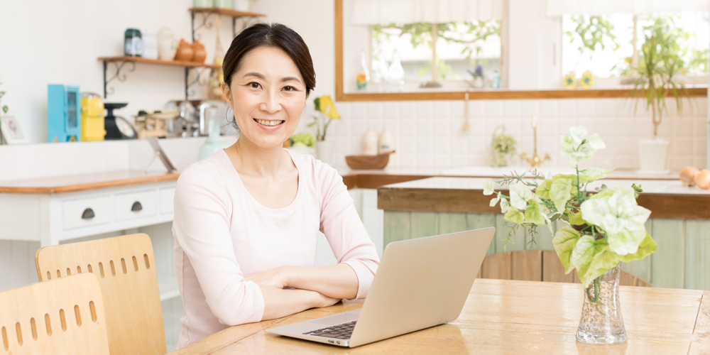ノートPCの前で腕組みする女性