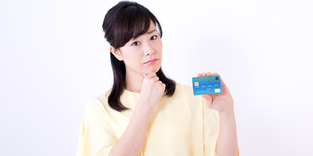 クレジットカードを持って悩む女性