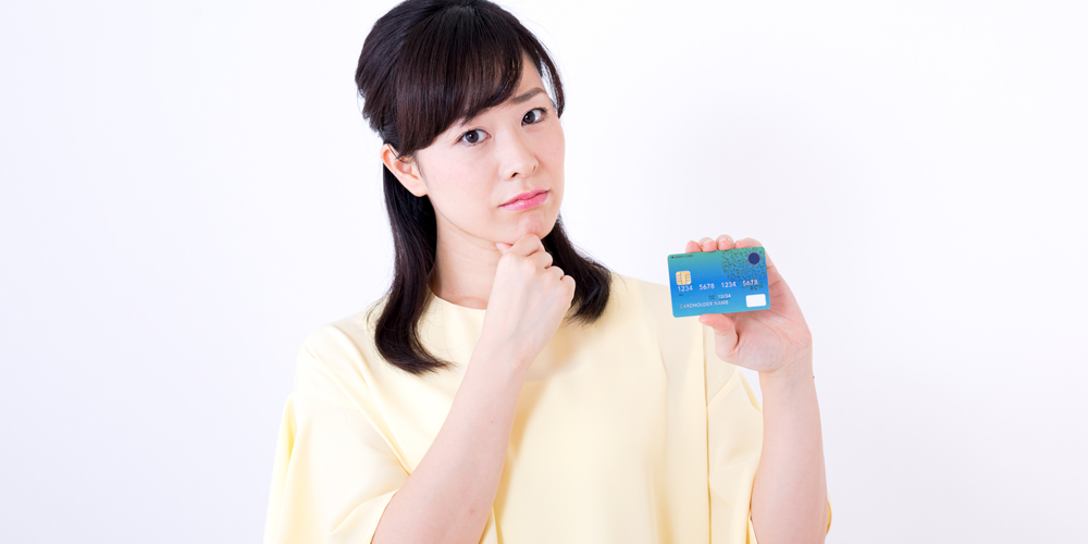 クレジットカードを持って悩んでいる女性