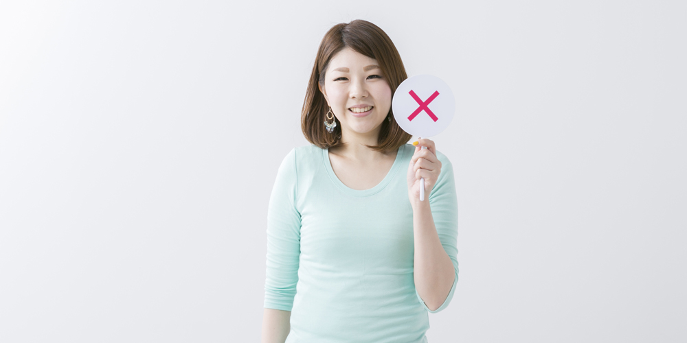 バツマークを持つ女性