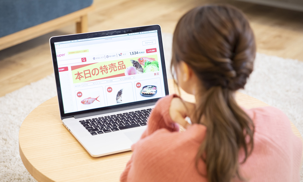 ノートPCでネットスーパーを見る女性