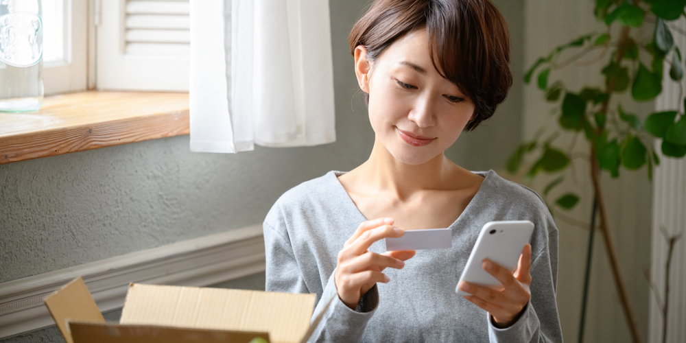 クレカを見ながらスマホを操作する女性