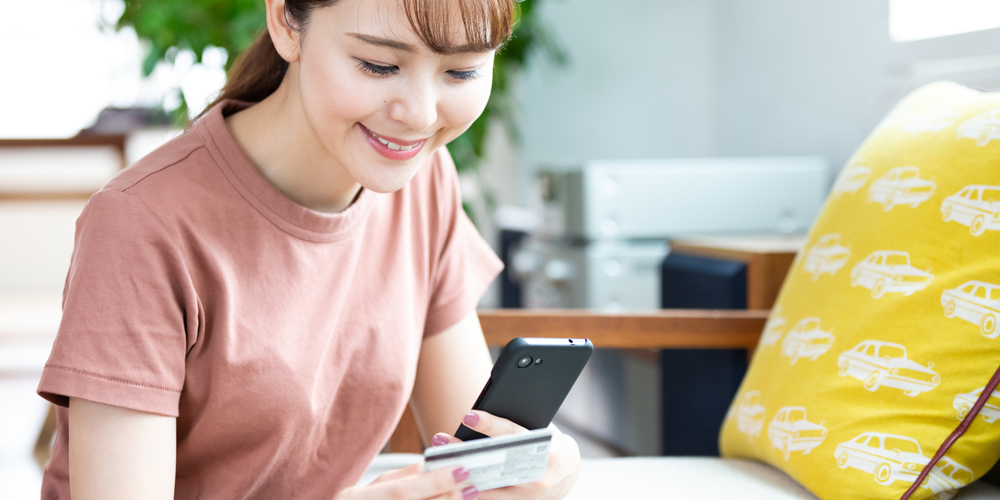 スマホを見ながらクレカを確認する女性