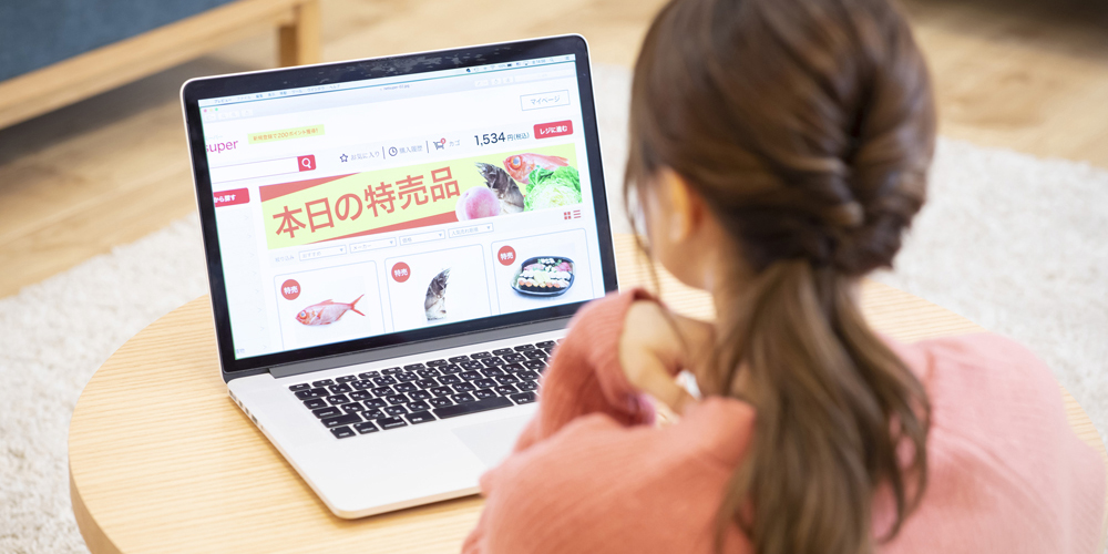 ノートPCでネットスーパーを見る女性