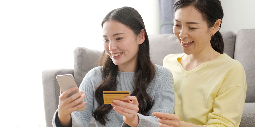 スマートフォンでクレジットカードを使う母娘