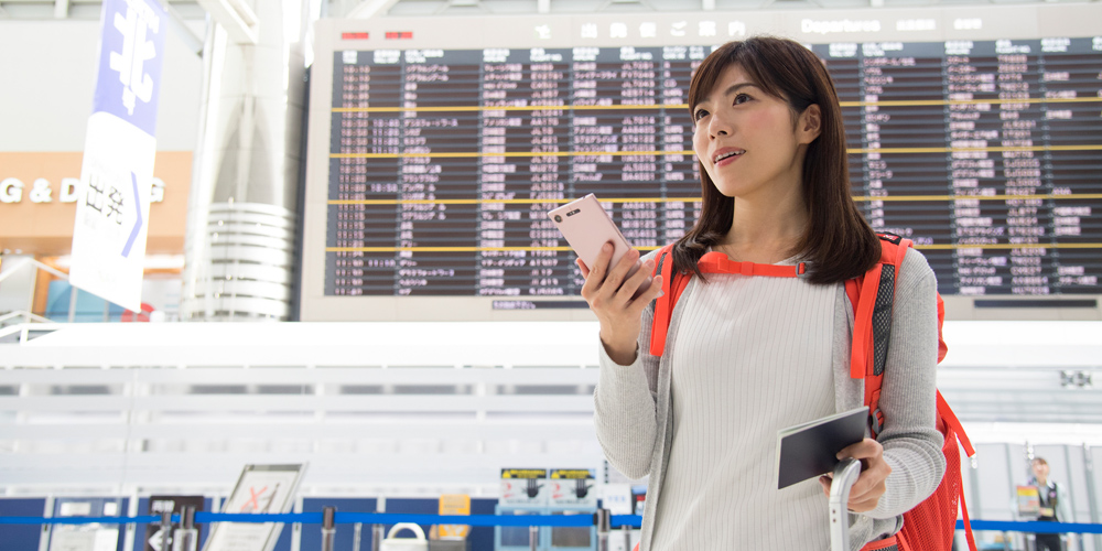 空港でスマートフォンを使う女性